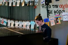 Μαθητής του Πειραματικού Λυκείου Πανεπιστημίου Μακεδονίας παρουσιάζει μουσική σύνθεση που δημιούργησε στο πλαίσιο του Προγράμματος, ενώ στο φόντο διακρίνονται δημιουργίες των μαθητών του  1ου Γυμνασίου Καισαριανής